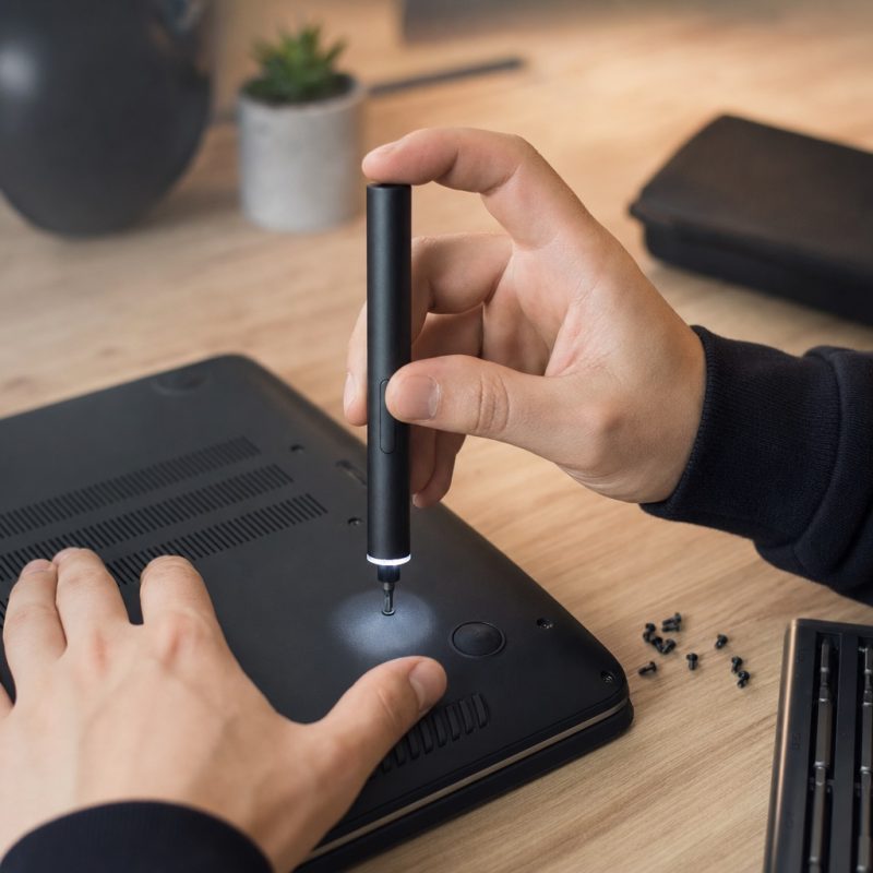 Electric screwdriver with LED light repairing a laptop